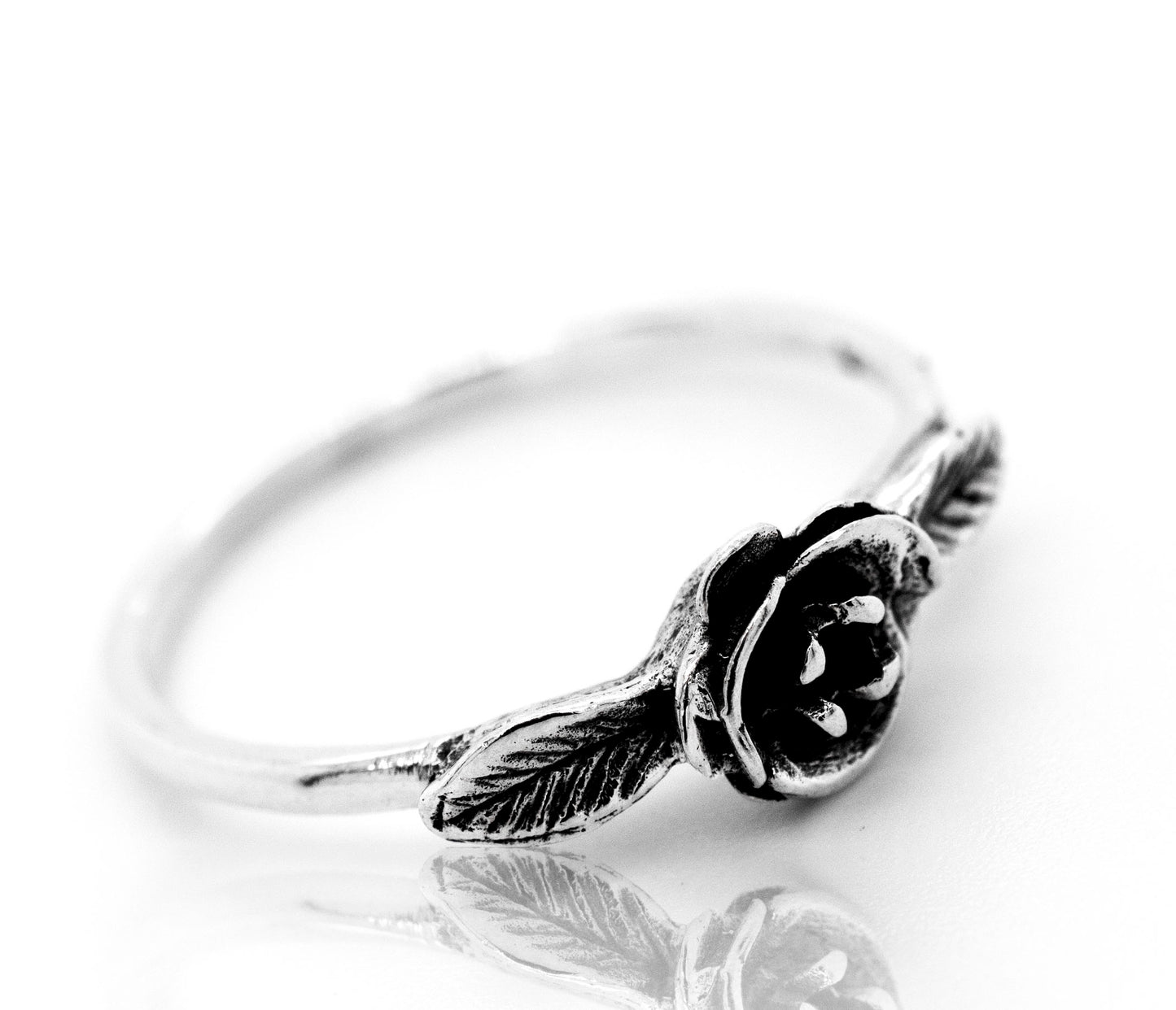 A floral silver ring with the Fashionable Rose Ring on it.