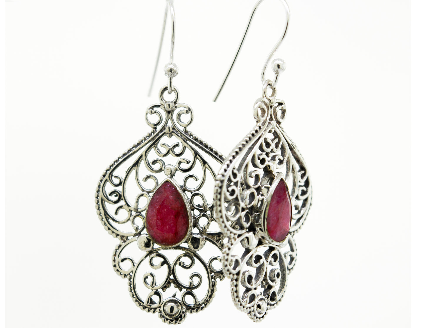 A pair of Teardrop Ruby Earrings With Freestyle Silver Design by Super Silver, featuring a vibrant teardrop-shaped ruby stone, set in a silver setting.