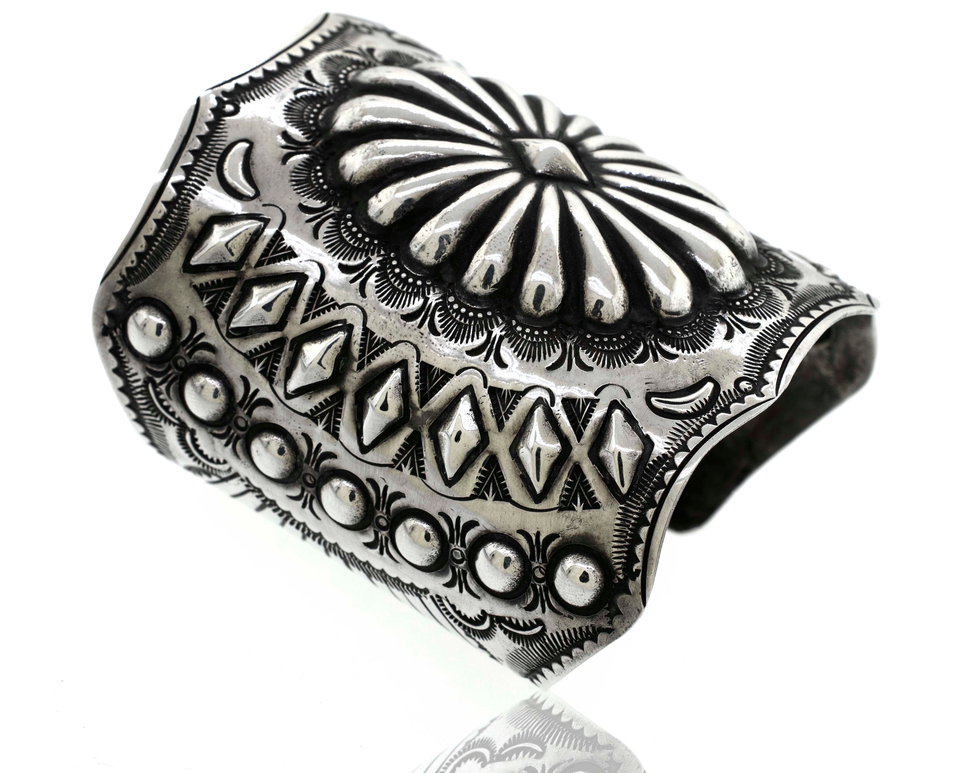 *Handcrafted Silver Concho Cuff* with intricate engraved patterns, including geometric shapes, floral motifs, and rows of raised dot accents, reminiscent of a traditional Native American concho cuff.