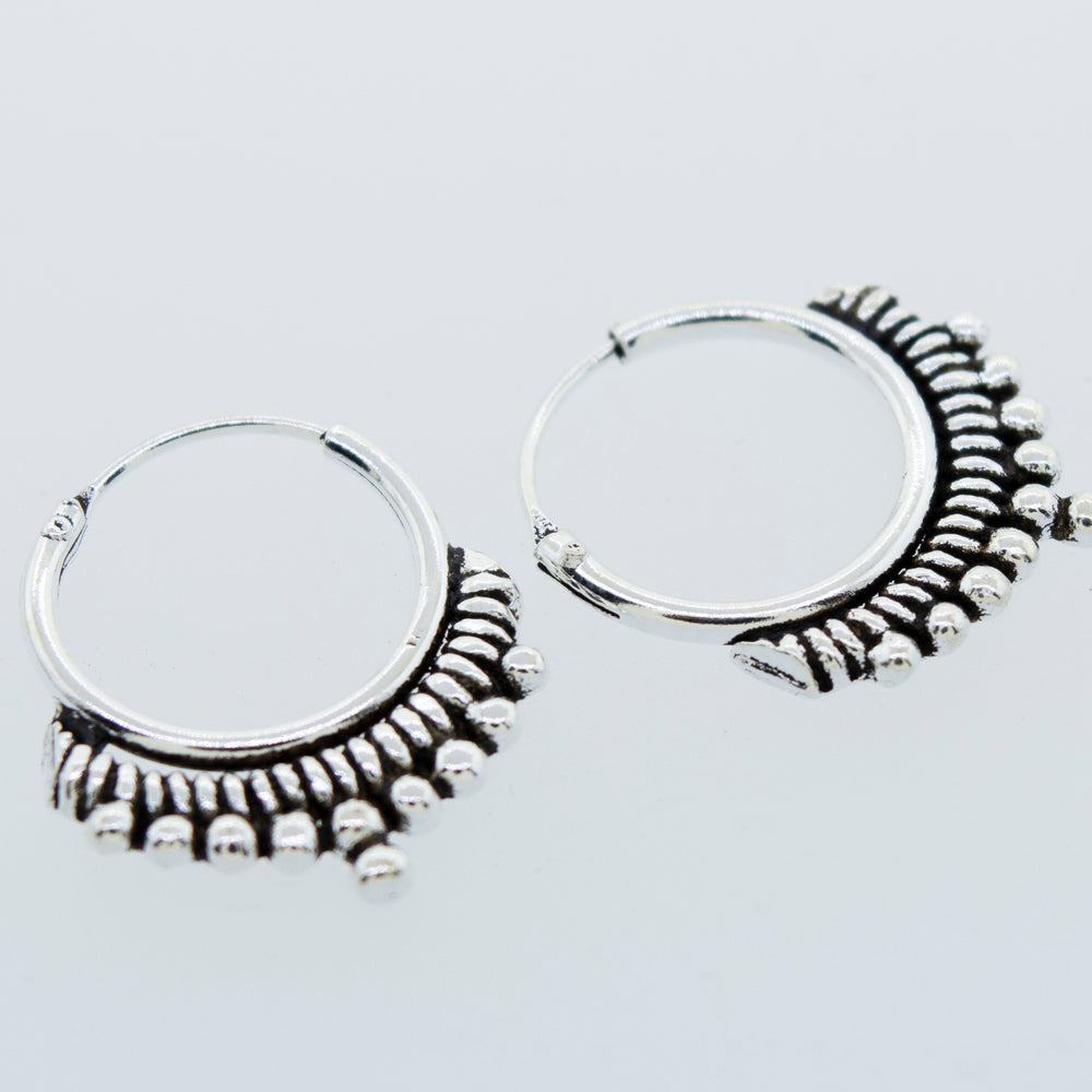 
                  
                    A pair of Small Freestyle Rope and Ball Hoop Earrings by Super Silver with a ball pattern on a white background.
                  
                