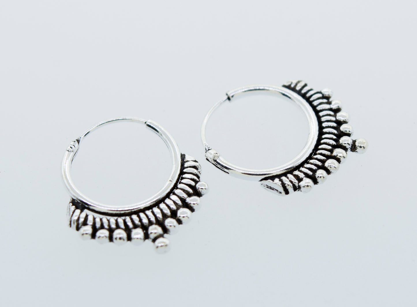 
                  
                    A pair of Small Freestyle Rope and Ball Hoop Earrings by Super Silver with a ball pattern on a white background.
                  
                