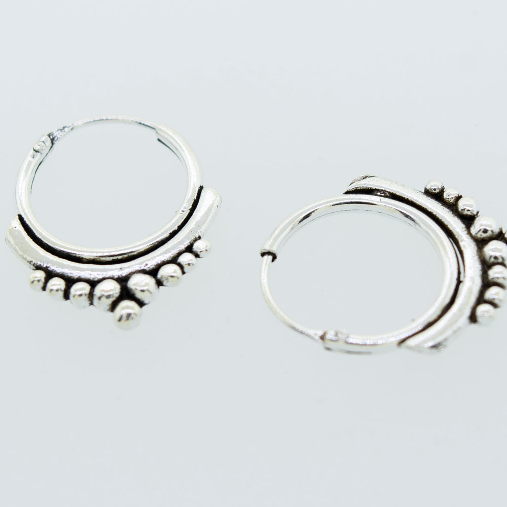 A pair of Super Silver Small Freestyle Ball Hoop earrings on a white surface.