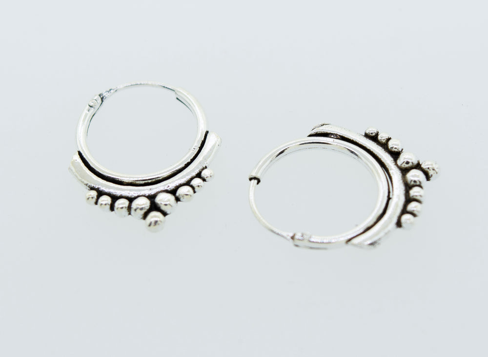 A pair of Super Silver Small Freestyle Ball Hoop earrings on a white surface.