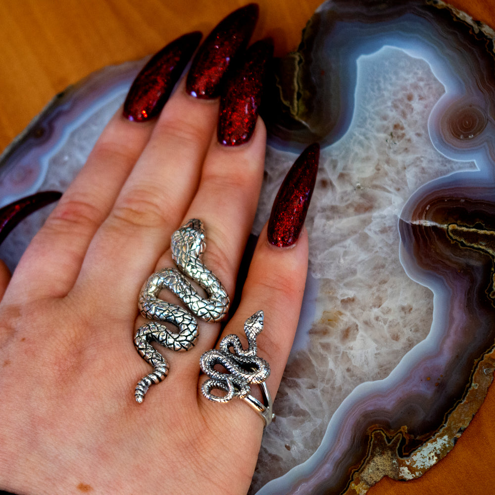 
                  
                    The Long Alluring Snake Ring delicately adorns a woman's hand, resting gracefully atop an exquisite agate.
                  
                