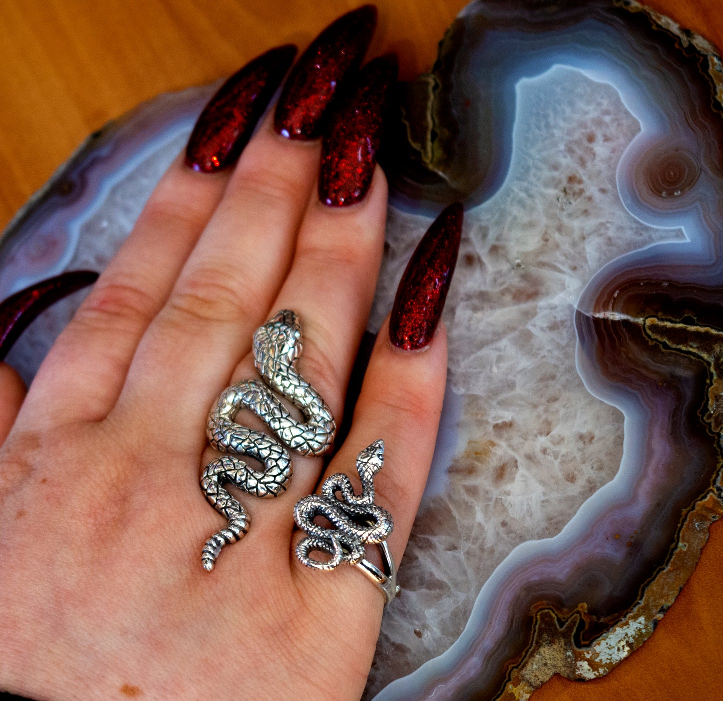 
                  
                    The Long Alluring Snake Ring delicately adorns a woman's hand, resting gracefully atop an exquisite agate.
                  
                