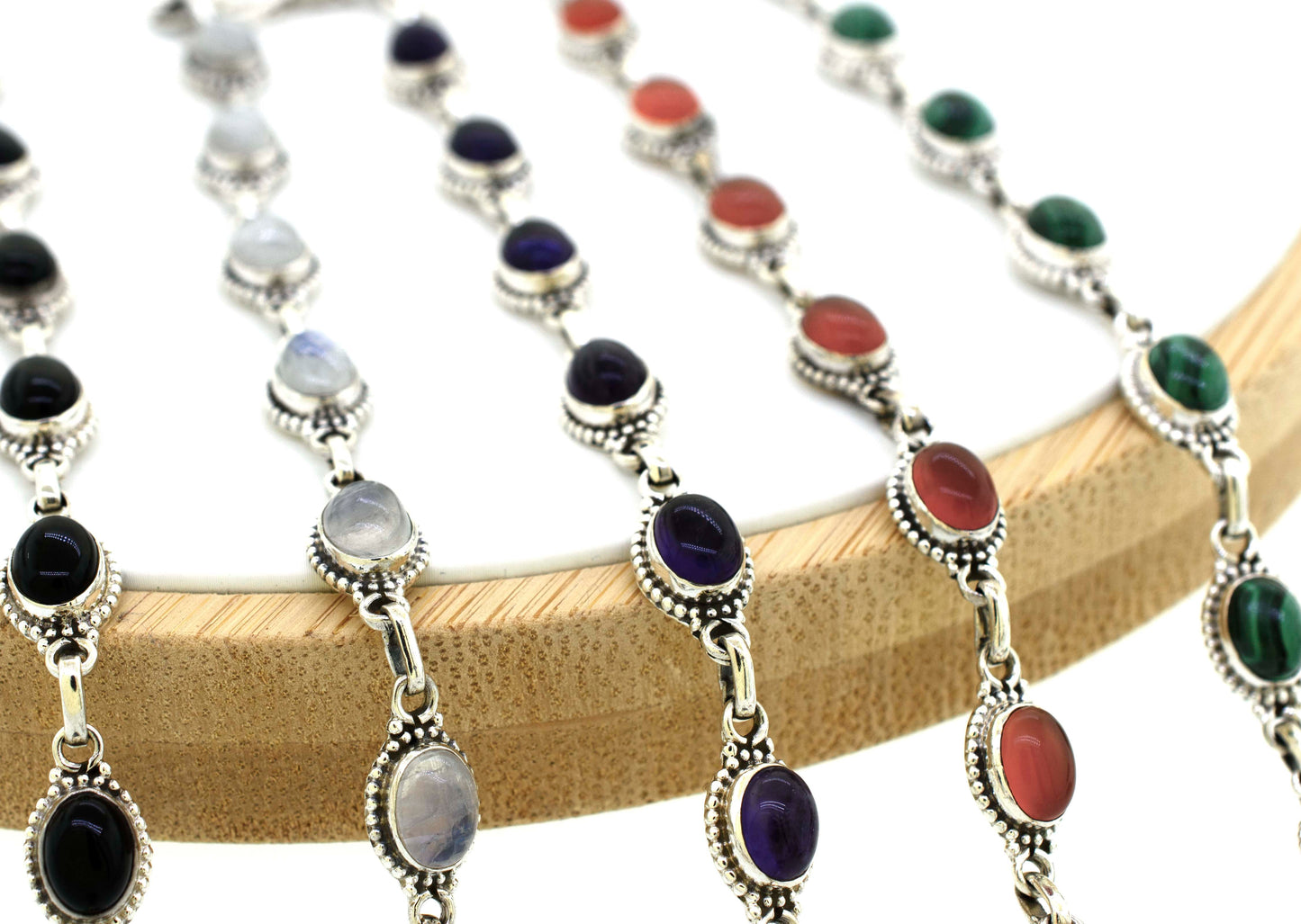 
                  
                    A group of Super Silver Oval Gemstone Bracelets With Ball Border on a wooden holder.
                  
                