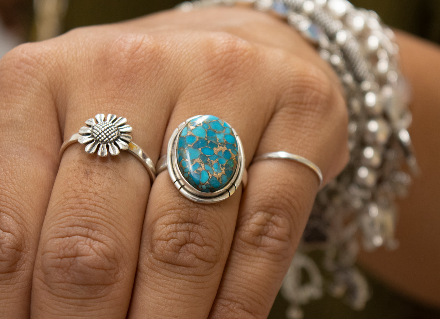 A woman's hand adorned with a beautiful Super Silver ring featuring an exquisite oval Natural Blue Copper Turquoise stone.