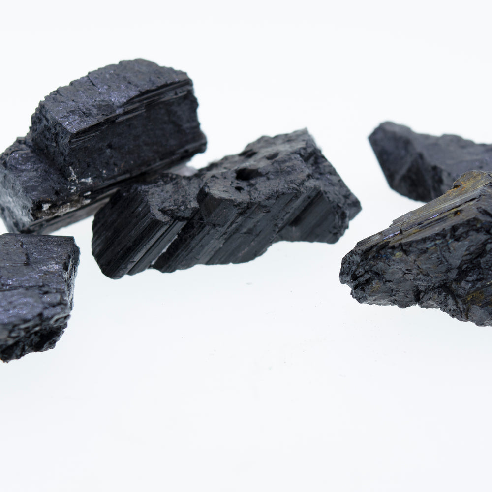 
                  
                    A stack of Rough Black Tourmaline Crystals on a white background.
                  
                