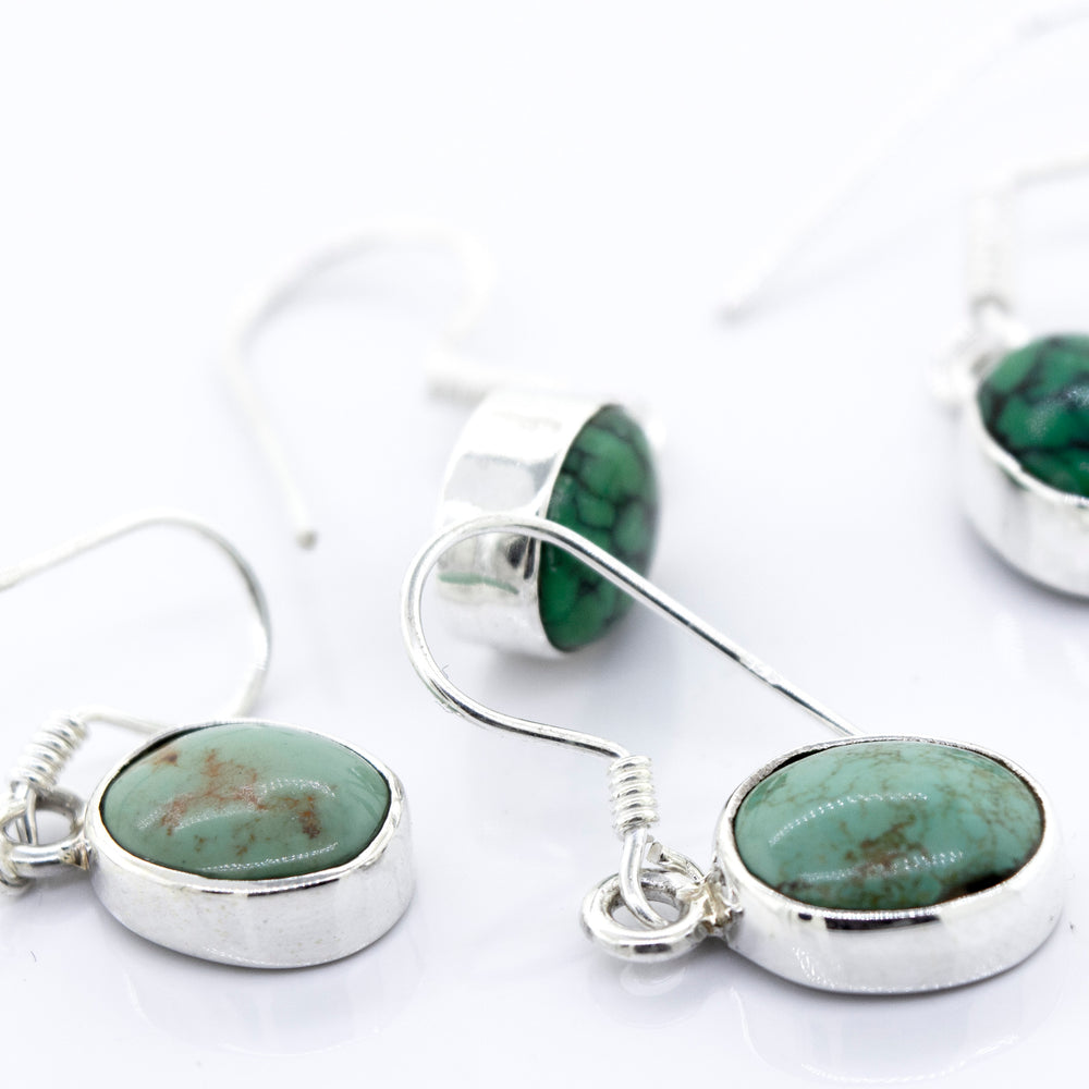 A pair of Super Silver oval natural turquoise dangle earrings with oval-shaped green stones.