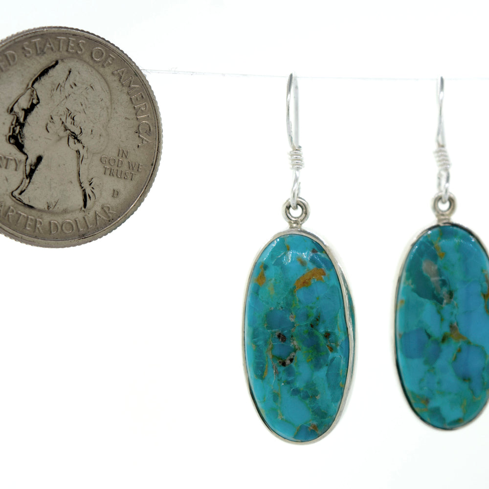 These Beautiful Oval Shape Composite Turquoise Earrings by Super Silver feature a dime, adding a touch of uniqueness to your summer outfit. Made with sterling silver for durability and style.