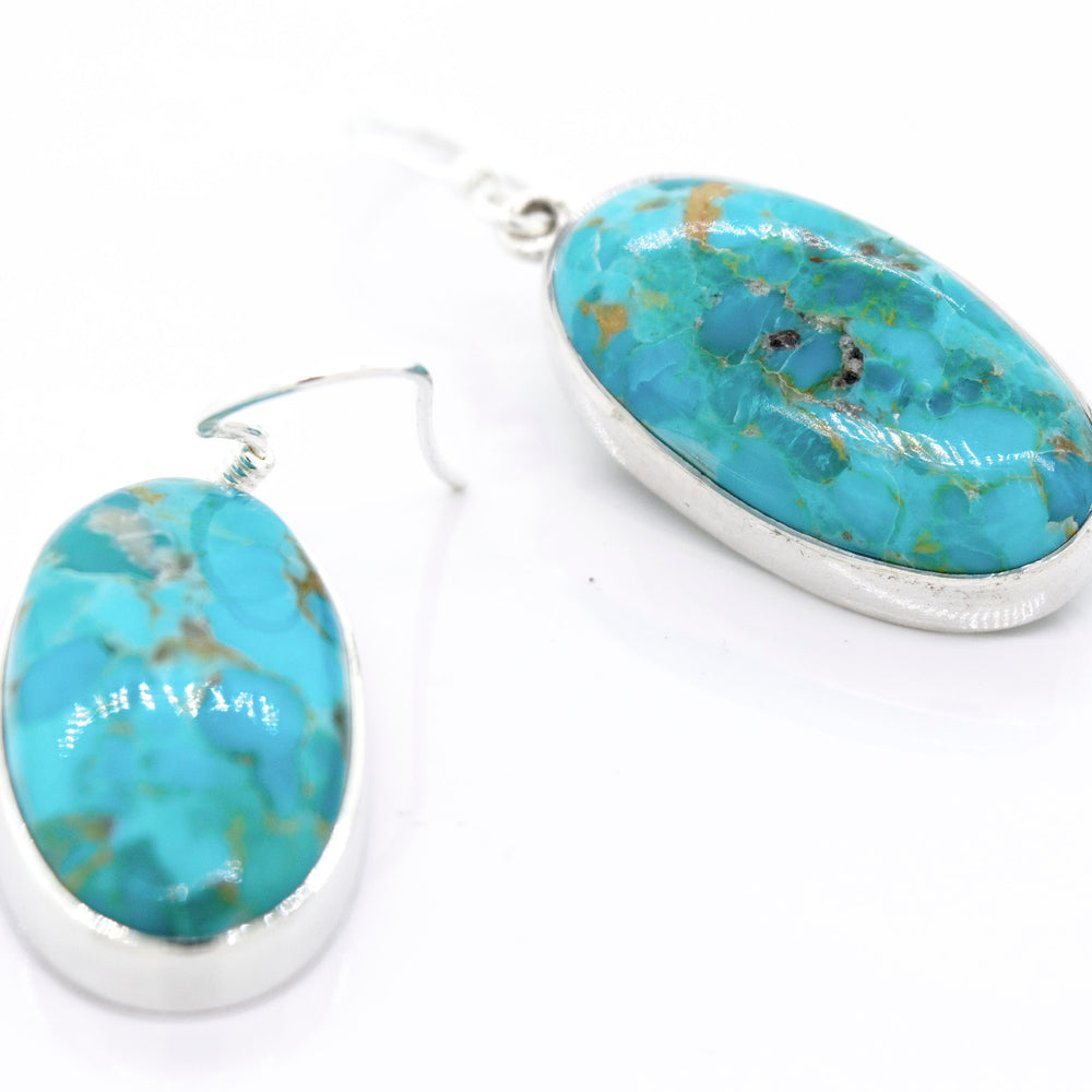 A pair of Super Silver Beautiful Oval Shape Composite Turquoise Earrings on a white surface.