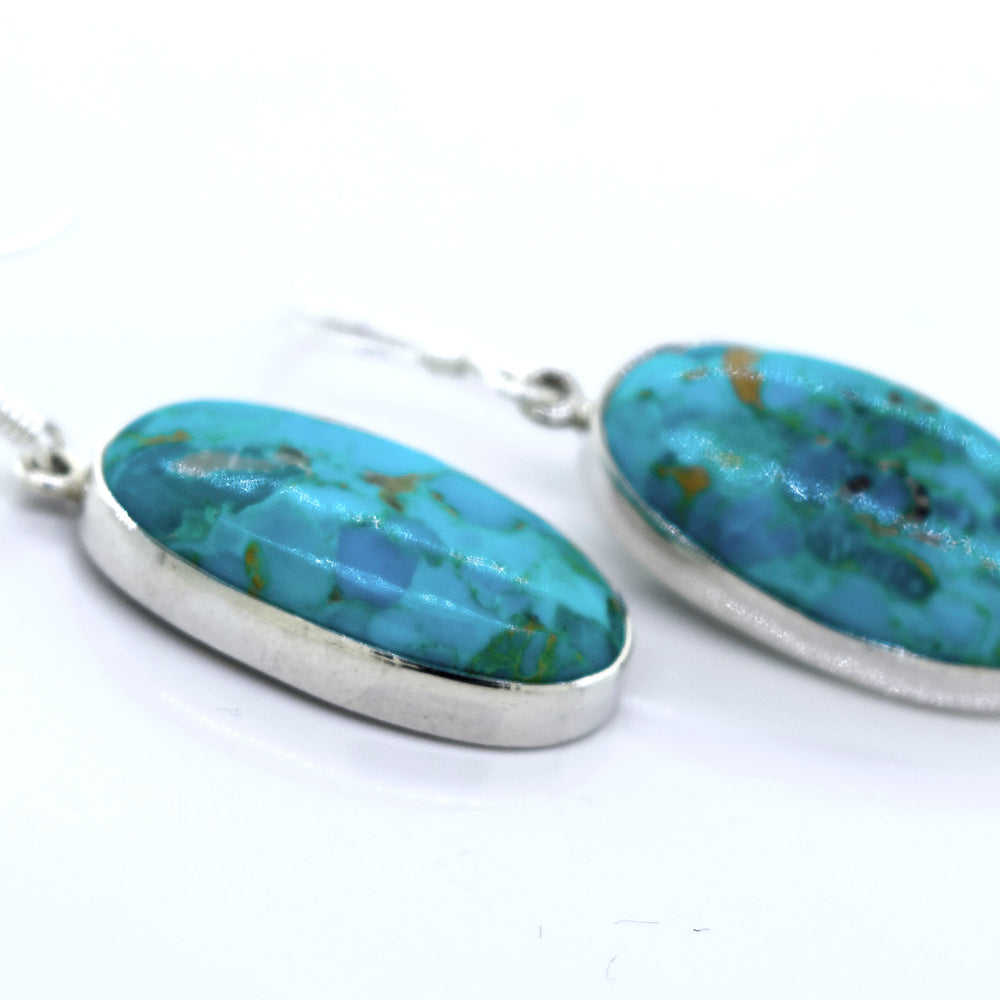 
                  
                    A pair of Beautiful Oval Shape Composite Turquoise Earrings by Super Silver on a white surface.
                  
                