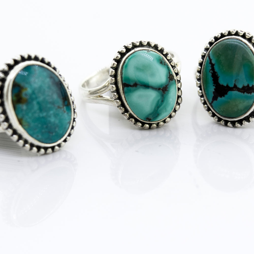 Three Super Silver Oval Natural Turquoise rings featuring a ball design on a white surface.