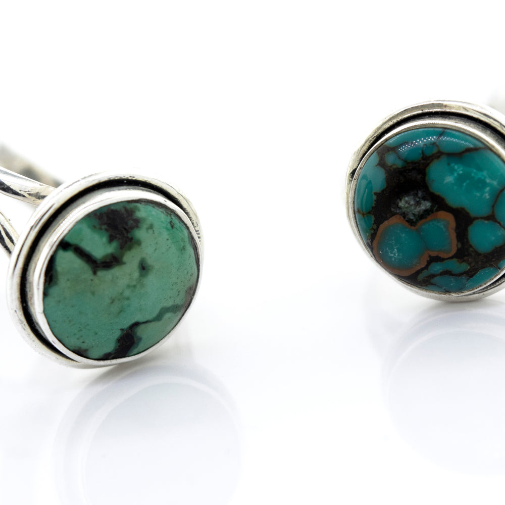 A pair of Super Silver Round Natural Turquoise Ring With Plain Border cufflinks resting on a white surface.
