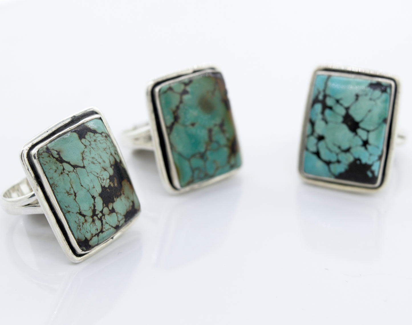 
                  
                    Three Rectangular Natural Turquoise Rings With Plain Border by Super Silver on a white surface.
                  
                