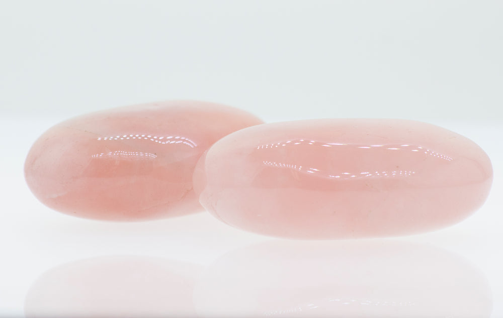 
                  
                    Two Rose Quartz Worry Stones on a white surface.
                  
                