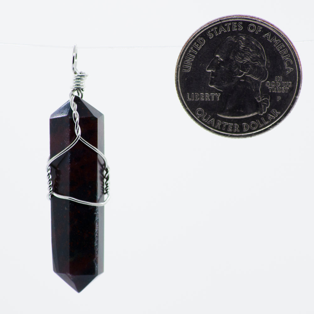 
                  
                    A Wire Wrapped Stone Pendant with a red garnet stone hanging from it, by Super Silver.
                  
                