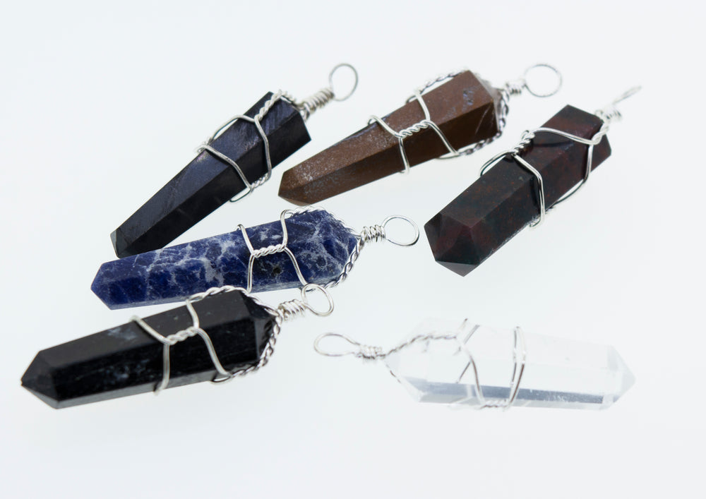 A group of Super Silver wire wrapped stone pendants on a white surface.
