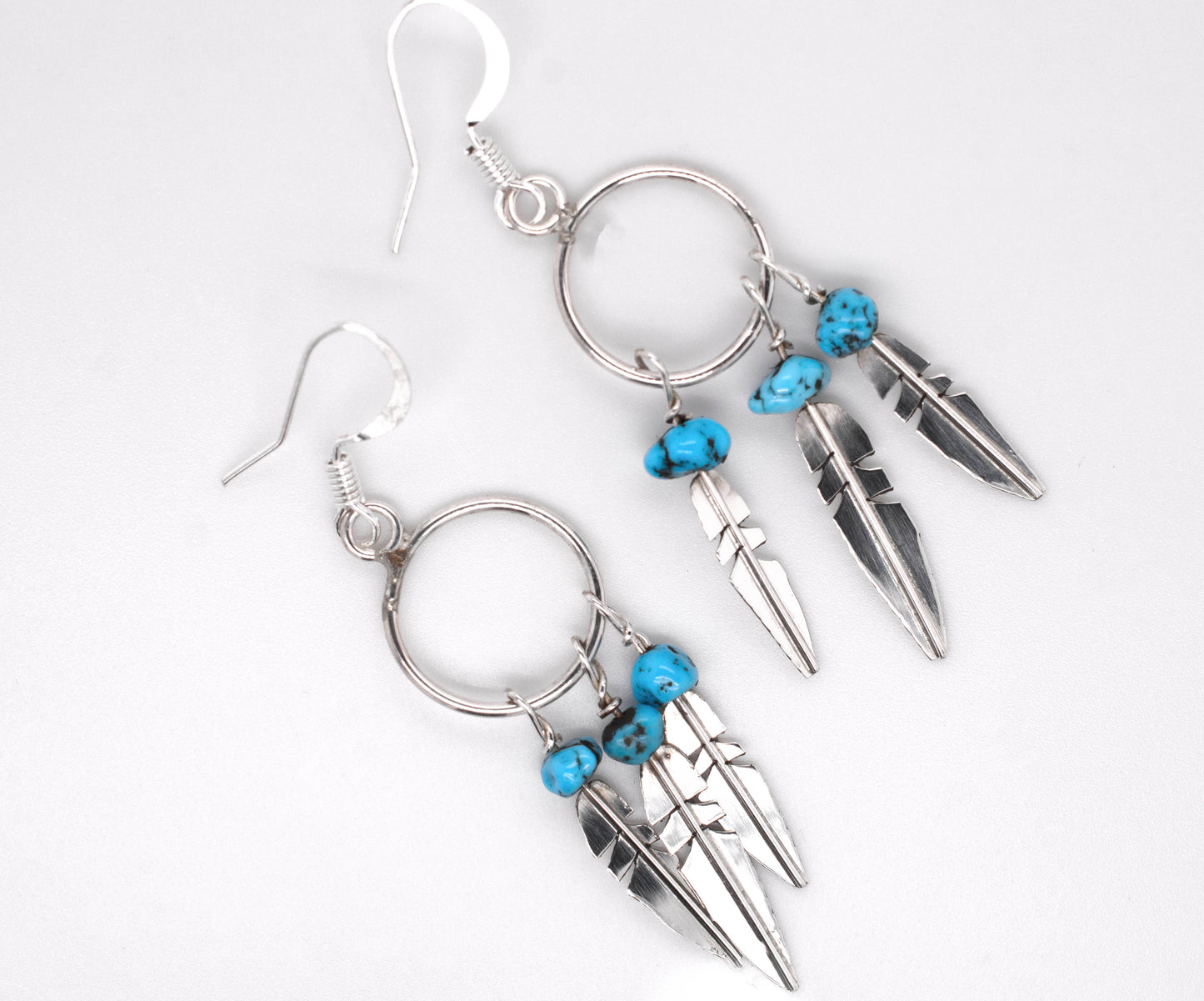 
                  
                    A pair of Super Silver Enchanting Zuni Feather Earrings with Coral or Turquoise beads.
                  
                