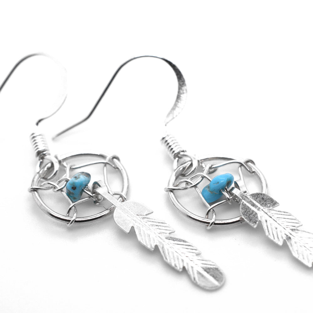 A stunning pair of Super Silver Zuni Turquoise Dreamcatcher Earrings adorned with turquoise stones and feathers.