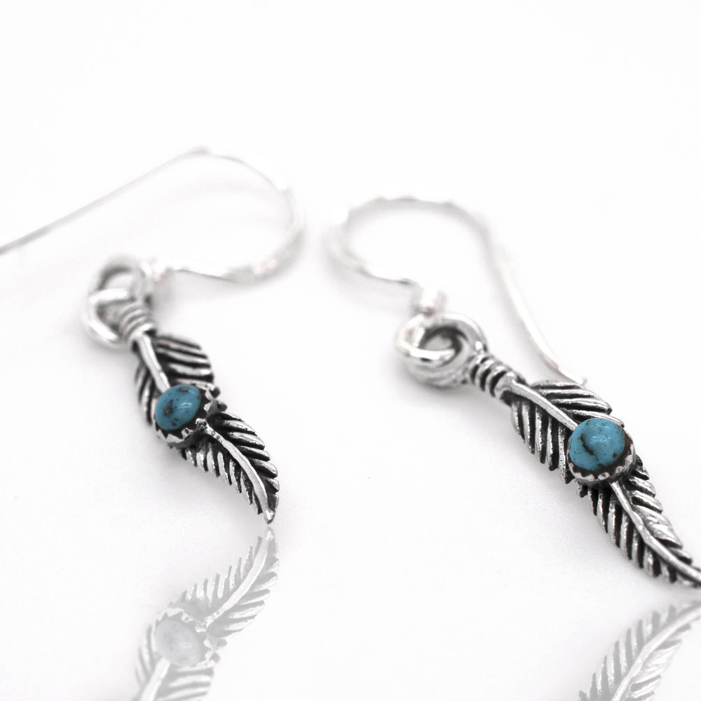 
                  
                    Super Silver's Delicate Feather Earrings adorned with vibrant turquoise stones.
                  
                