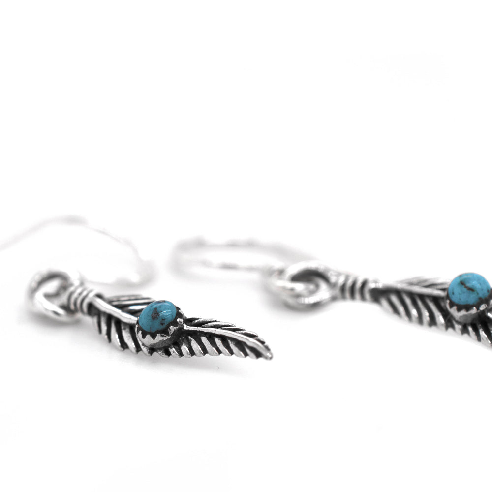 
                  
                    A pair of Super Silver delicate feather earrings adorned with vibrant turquoise stones.
                  
                